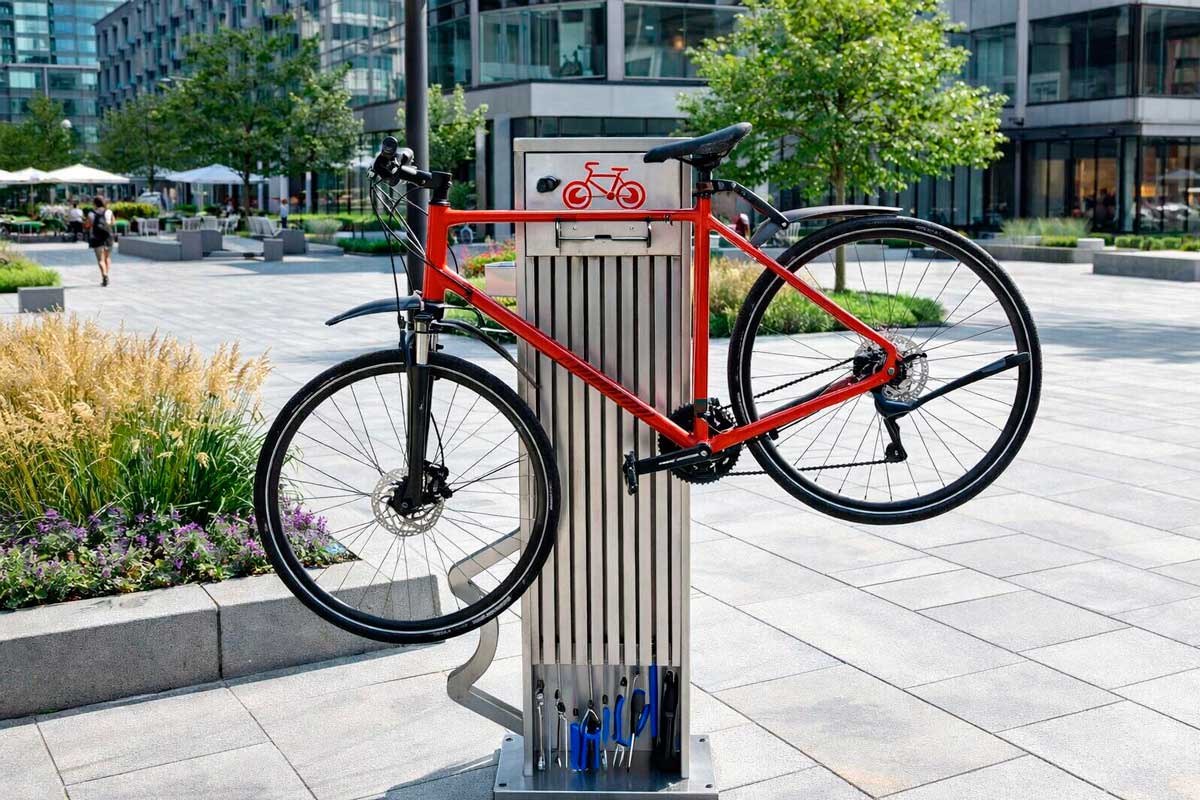 Columna de mantenimiento de bicicletas con herramientas y bomba de aire colgante en espacio urbano